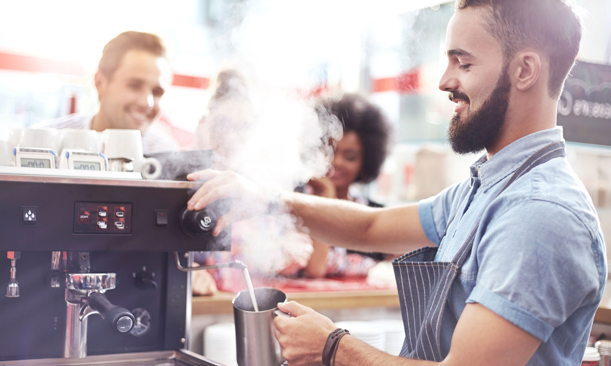 Barista skummar mjölk i ett café