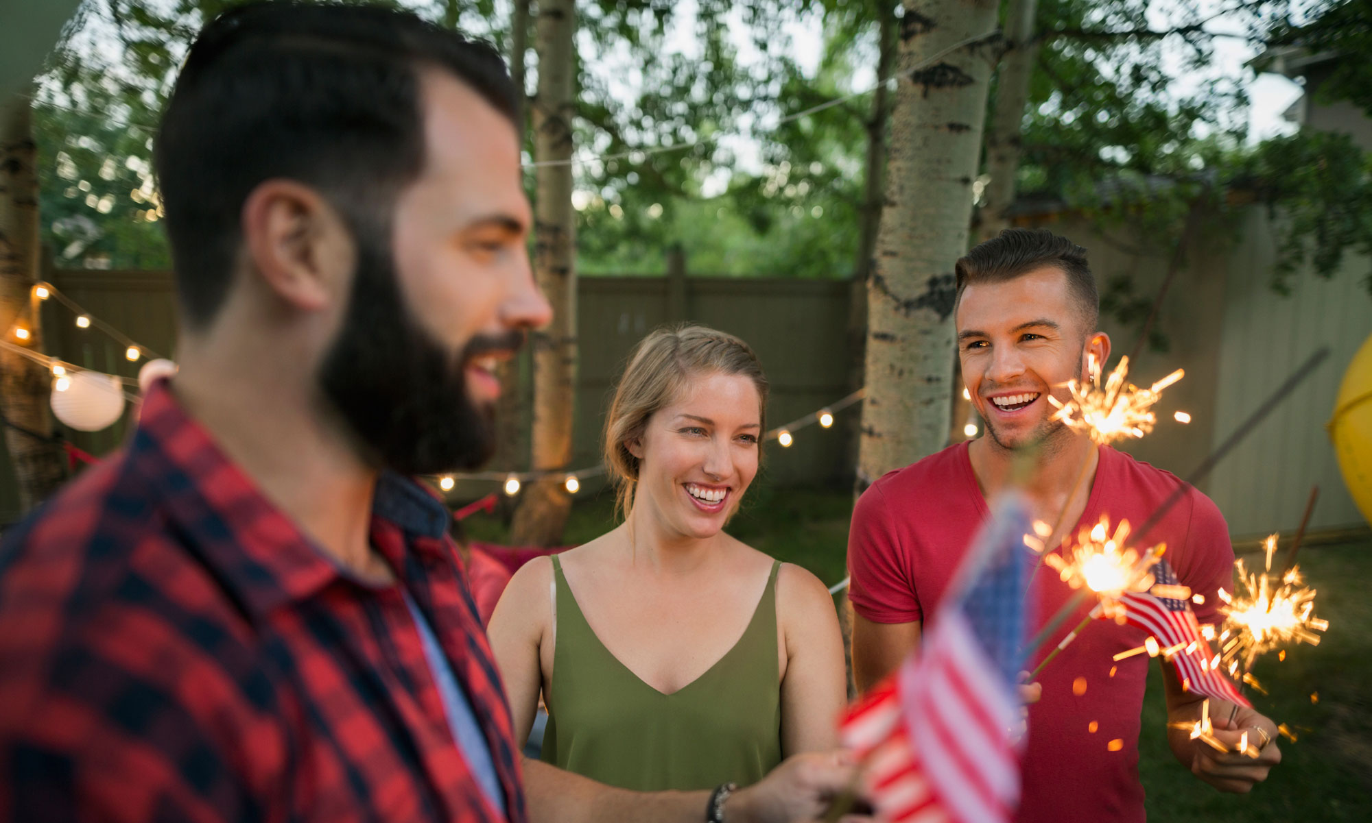 Glada vänner firar med tomtebloss och flaggor utomhus en sommarkväll 